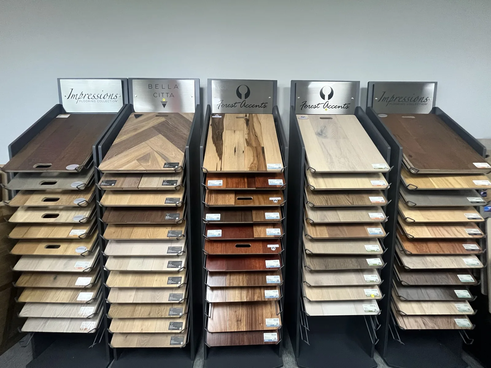 Full-size hardwood sample boards on pull-out racks — Impressions, Bella Citta and Forest Accents — At Home Flooring showroom, Wylie TX