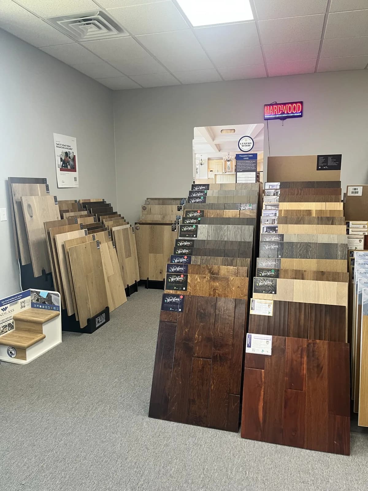 Hardwood sample racks and stair tread display under the HARDWOOD sign at the At Home Flooring showroom, 1001 Alanis Dr, Wylie TX
