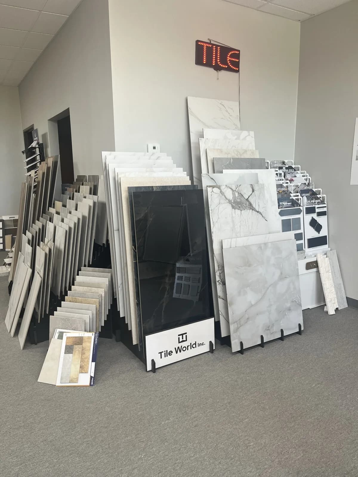 Large-format porcelain and marble-look tile slabs standing under the TILE sign, At Home Flooring showroom, Wylie TX