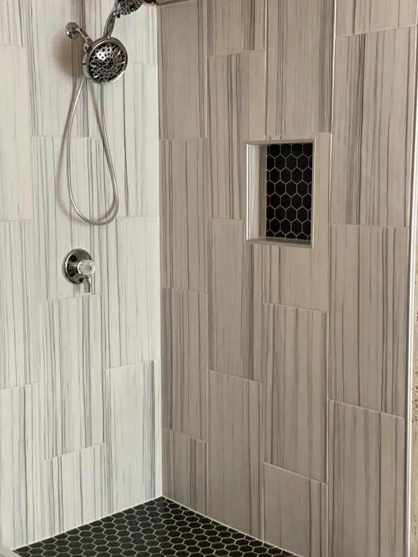Walk-in shower rebuilt in large-format striated porcelain with a black hexagon mosaic niche, McKinney TX